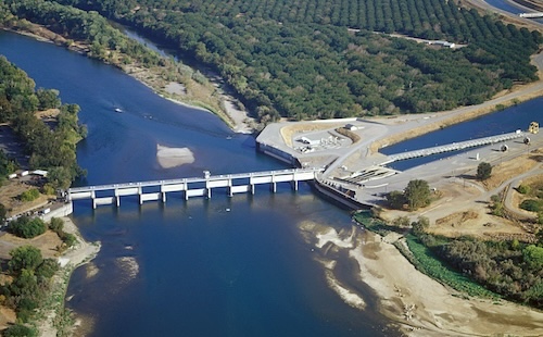 A dam on a river, with natural and production forests in the background